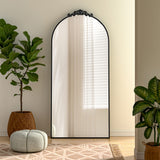 Black arched freestanding mirror with scrollwork metal frame, reflective glass