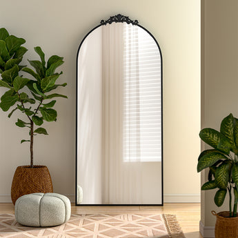 Black arched freestanding mirror with scrollwork metal frame, reflective glass