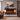 Wall-mounted electric fireplace with dark mantel and orange flames behind front panel