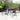 Outdoor dining table with 4 dark woven armchairs, curved frames, and glass tabletop