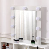 Lit bulb mirror on white makeup vanity with countertop bottles and cosmetics