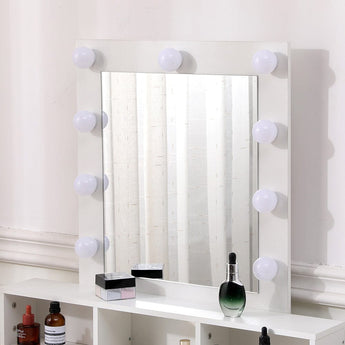 Lit bulb mirror on white makeup vanity with countertop bottles and cosmetics