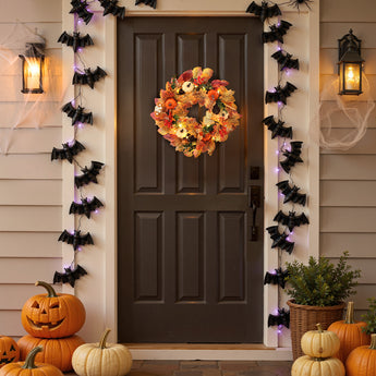 Halloween wreath with orange floral foliage, pumpkin, and owl accents on dark door