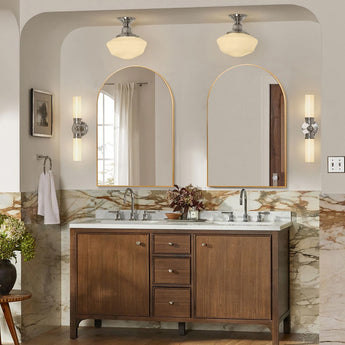 Arch-shaped gold-framed wall mirror above a vanity with built-in lights