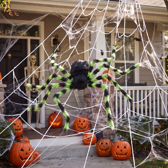 Giant Halloween spider decoration with green-striped legs and white web across doorway