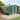 Dark green metal garden storage shed with apex roof and side door opening