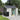 Outdoor garden tool shed with double doors, black roof, and white window panels