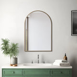 Arch-shaped gold-framed wall mirror above a green vanity and white sink