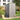 Grey plastic garden storage shed with front door open and handle, lockable latch