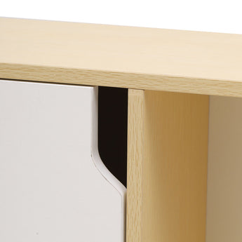 Close-up of curved cutout detailing on white door front of the wooden cabinet