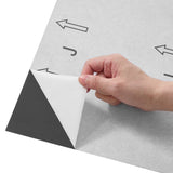 Peel-and-stick vinyl floor tile sheet, hand lifting corner with arrows
