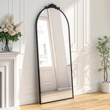 Black arched freestanding mirror with ornate metal top frame, full-length view