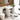 White corner bathroom vanity with ceramic sink, open cabinet doors, and inner shelving