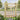 Wooden outdoor gate with X-brace top, vertical bars, and black hinges