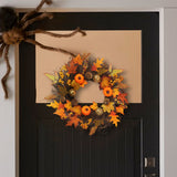 Halloween wreath hanging on door, orange and black leaves with pumpkins and pinecones