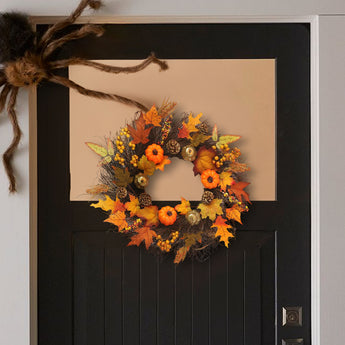 Halloween wreath hanging on door, orange and black leaves with pumpkins and pinecones