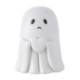 Small white ghost figurine with sad face, closed hands at chest