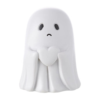 Small white ghost figurine with sad face, closed hands at chest