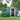 Dark green metal garden storage shed with sliding door open showing shelves inside