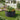 Dark grey round metal raised garden bed with mixed herbs, flowers, and tomatoes