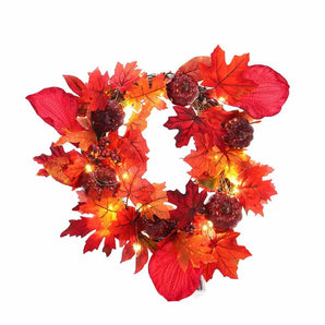 Nahaufnahme: Herbstkranz mit Ahornblättern, Beeren und warmen LED-Lichtern, rot-orange