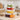 Clear fridge food storage containers with white snap lids, stacked with assorted produce