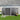 Lockable gray metal garden storage shed with double doors and apex roof, side view.