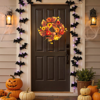 Halloween autumn wreath with orange and yellow flowers and warm LED-style lights