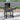 Portable charcoal BBQ grill with side shelf, wheels, and open lid; food on grates