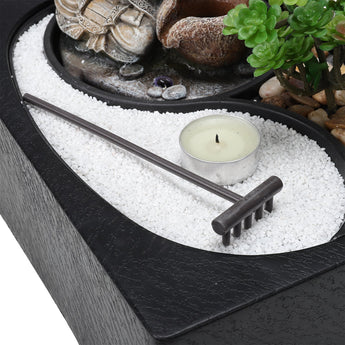 Teelicht in Metallhalter im Kiesbett mit Buddha-Figur und Sukkulente rechts