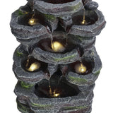 Faux rock garden fountain close-up, glowing lights inside tiered stone water basins.