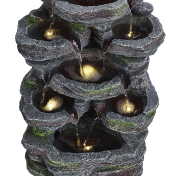Faux rock garden fountain close-up, glowing lights inside tiered stone water basins.