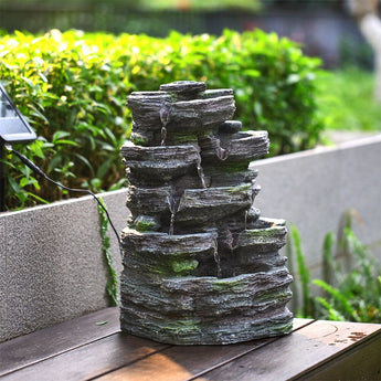 Faux rock garden fountain on tabletop style surface, multi-tier water flow detail.
