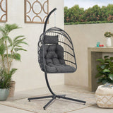 Black rattan hanging swing chair with stand and dark gray padded cushions
