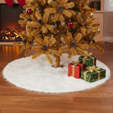 White plush Christmas tree skirt under decorated tree with red and green gifts
