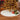 White plush Christmas tree skirt under decorated tree with red and green gifts