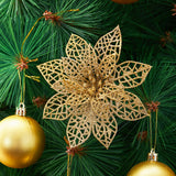 Gold sequined artificial poinsettia flower attached to green Christmas tree branches.