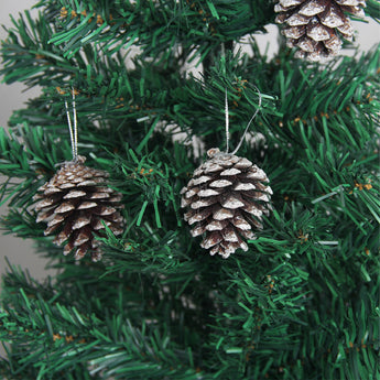 Pine cone hanging ornament with white-painted scales on green Christmas tree branches