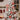 Red wooden hanging ornaments on white tree: star, gingerbread house, ginger man, barn
