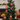 Red wooden hanging ornaments on green tree: barn, star, gingerbread house, horse