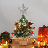 Mini artificial Christmas tree with silver star topper, warm lights, pinecones and red ornaments