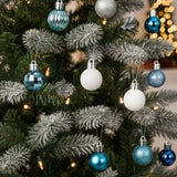 Christmas ball ornaments on fir branches: blue, white, and silver textured baubles