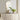 Gold oval wall mirror with slim frame above a white dresser and potted plant.
