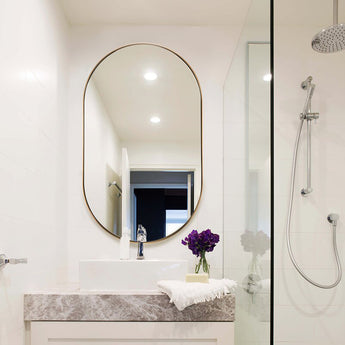 Gold oval metal wall mirror with thin edge frame, reflective glass surface