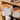 White pet food storage bin with orange flip-top lid opened on wooden shelf