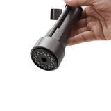 Grey pull-down spray head held in hand, showing multi-hole nozzle on faucet
