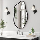 Irregular wall mirror with black metal frame, arched oval shape on bathroom wall