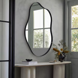 Irregular wall mirror with black metal frame, rounded oval silhouette above console