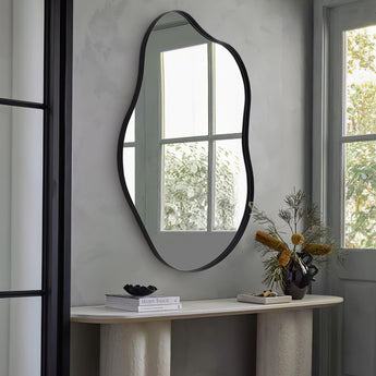Irregular wall mirror with black metal frame, rounded oval silhouette above console