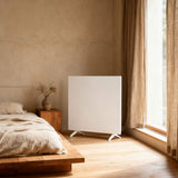 White freestanding convection heater on casters, front view near window